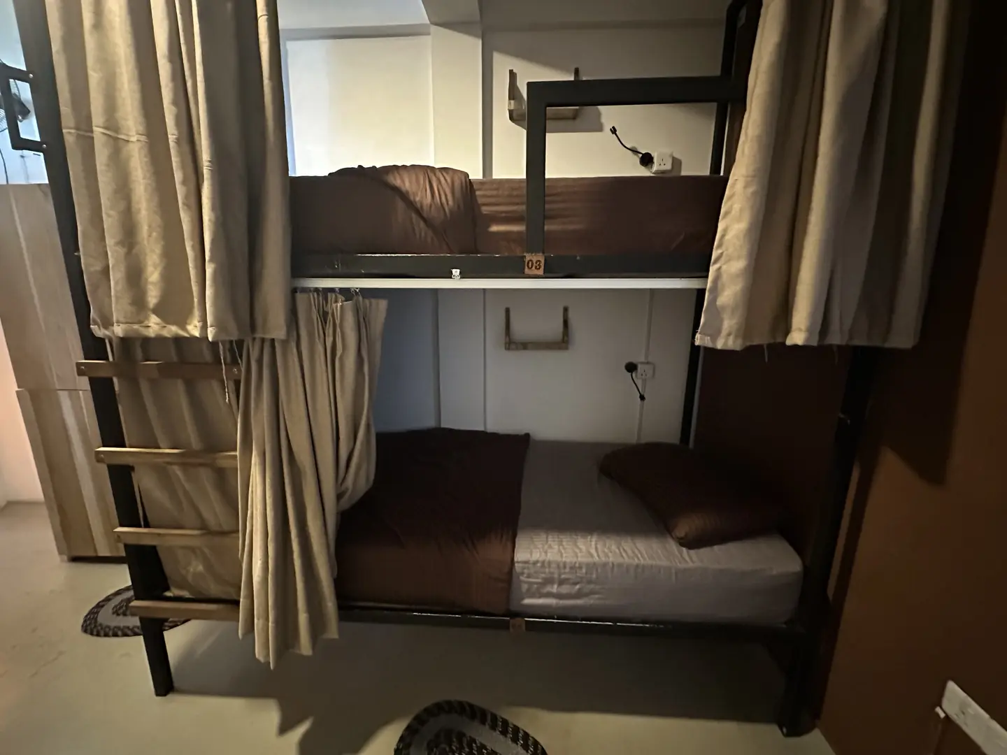 A dorm bed with curtains, light and a power socket
